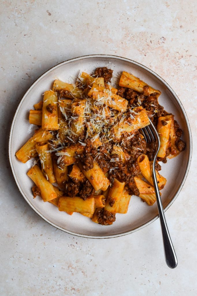 Venison Ragù with pasta and grated cheese in a shallow bowl.