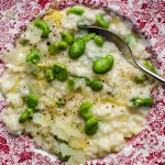 Close up of a bowl of broad bean risotto with lemon zest.