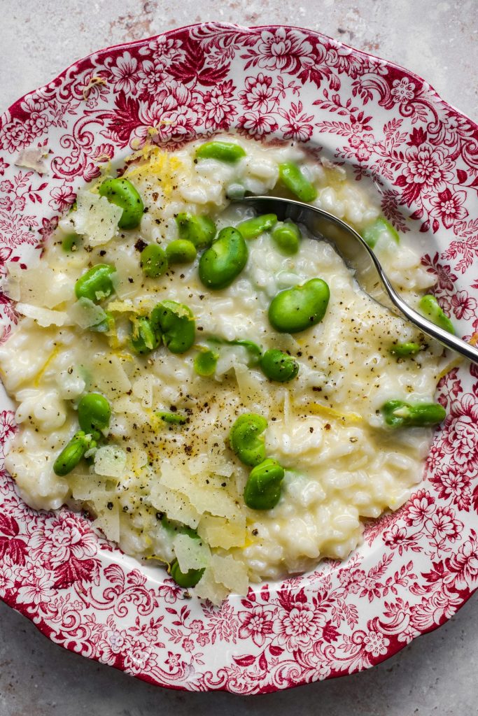 Close up of a bowl of broad bean risotto with lemon zest.