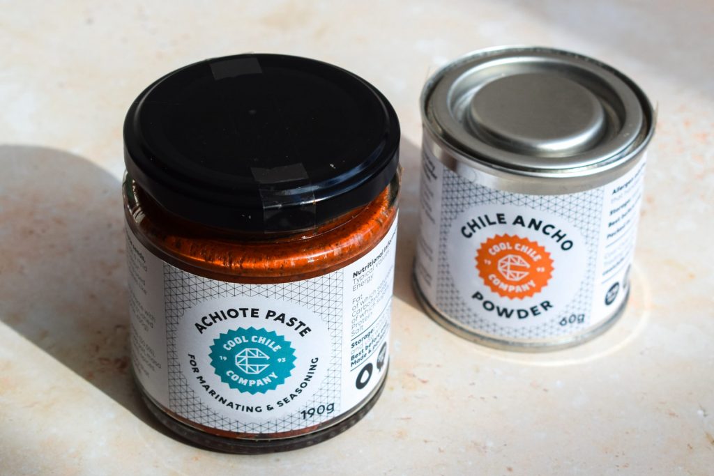 A jar of achiote paste and a tin of ancho chilli powder.