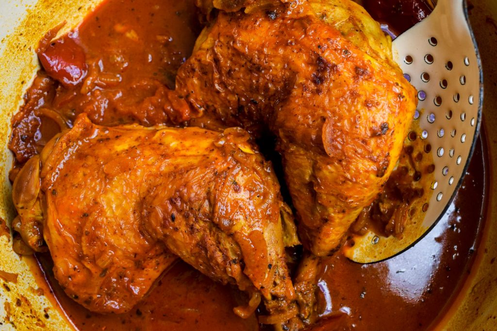 Close up of yellow braised chicken legs in achiote paste.