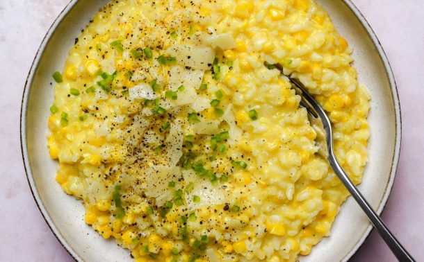 Bowl of corn risotto topped with cheese and chopped green chilli.